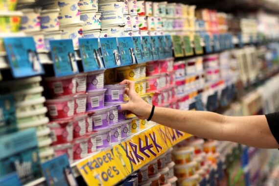 Hand reaching out for a yogurt in the refrigerator yogurt section at Trader Joe's, Pinecrest, Florida, selective focus, blurred surrounding yogurt packages