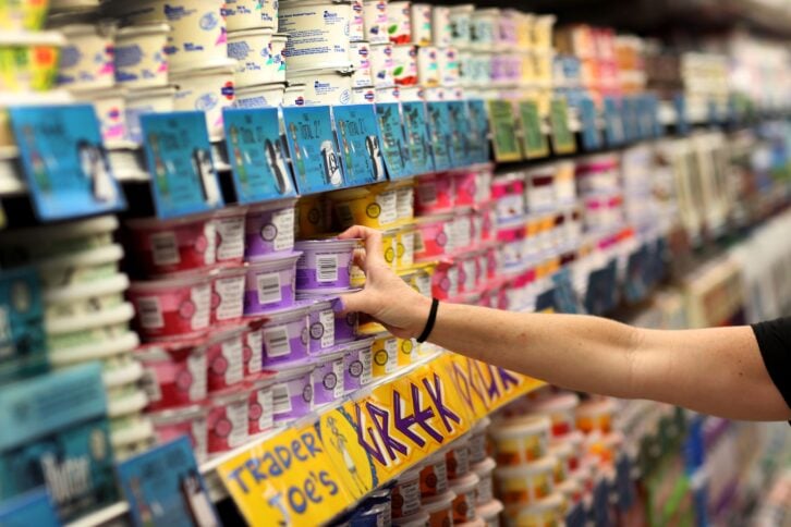 Hand reaching out for a yogurt in the refrigerator yogurt section at Trader Joe's, Pinecrest, Florida, selective focus, blurred surrounding yogurt packages