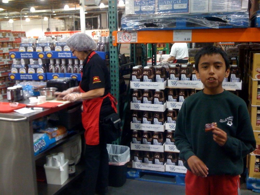 Kid stands to the side of Costco sample station