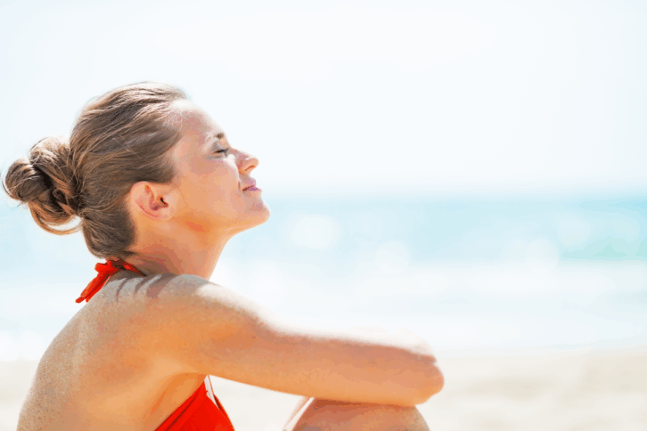 Woman relaxing on the beach looking up at the sky