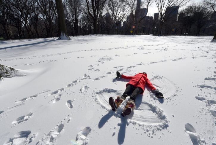 ara Jakeway with Chasing News makes a snow angel in the man-made snow in Central Park January 20, 2016 as part of Winter Jam NYC's Ultimate Snow Day.