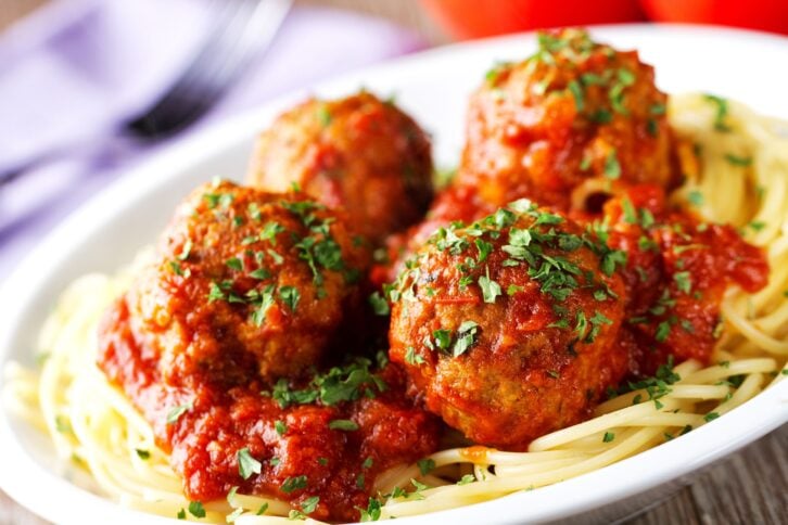 Spaghetti and meatballs on a white plate, selective focus, a slight diagonal with a blurred background of a fork and napkin