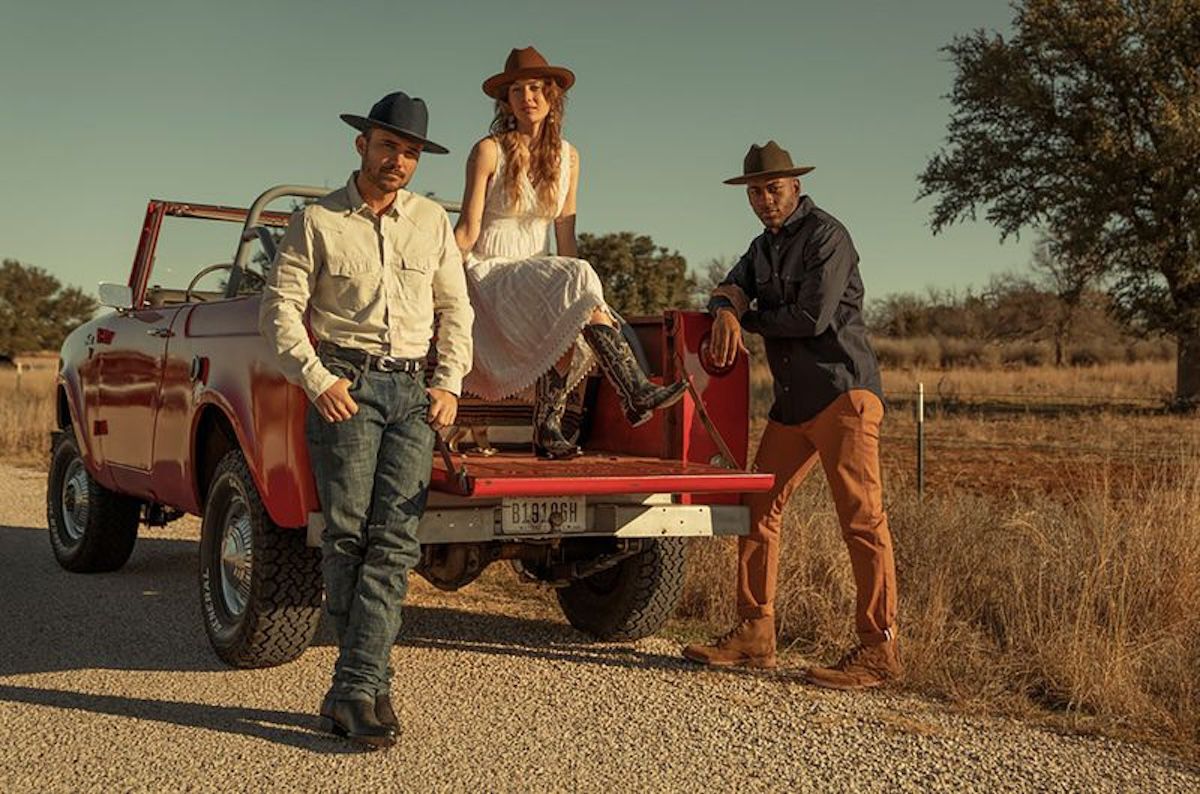 Two male and one female models around a red pickup truck wearing Stetson clothing
