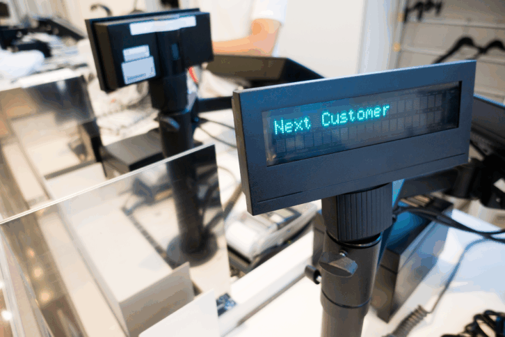 Closeup of a checkout register that says "Next Customer"