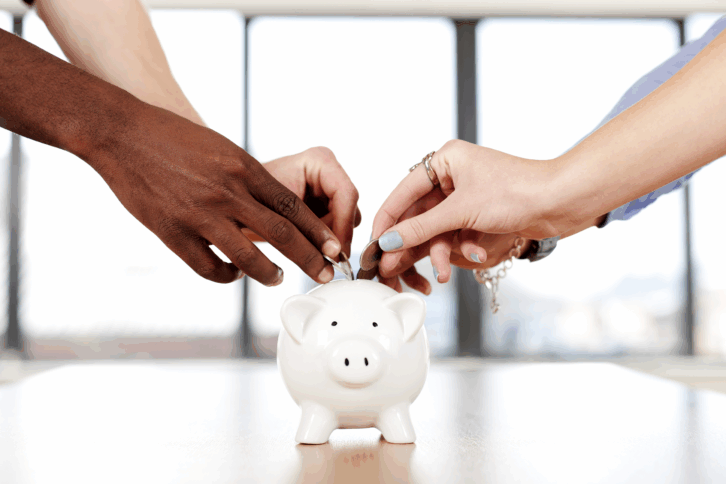People putting coins into a piggy bank