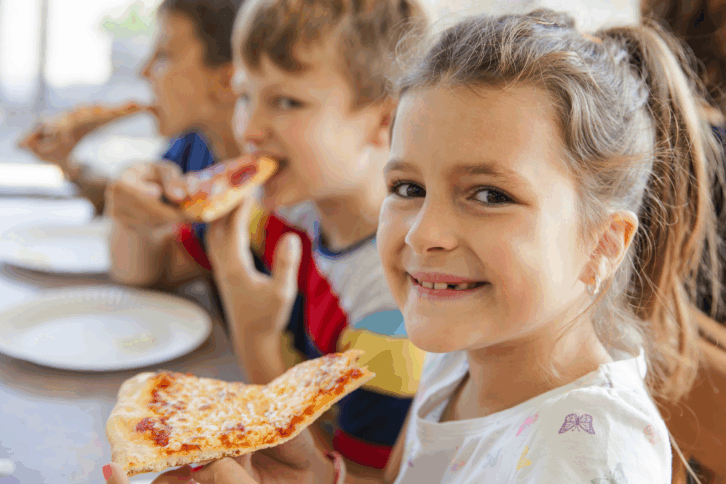 Young children eating pizza in a restaurant