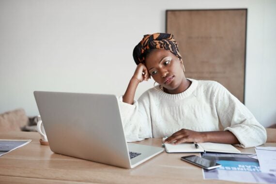 Shot of a young woman looking bored while working on a laptop