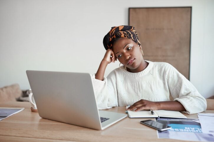 Shot of a young woman looking bored while working on a laptop