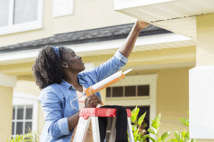 Woman on a ladder repairing home