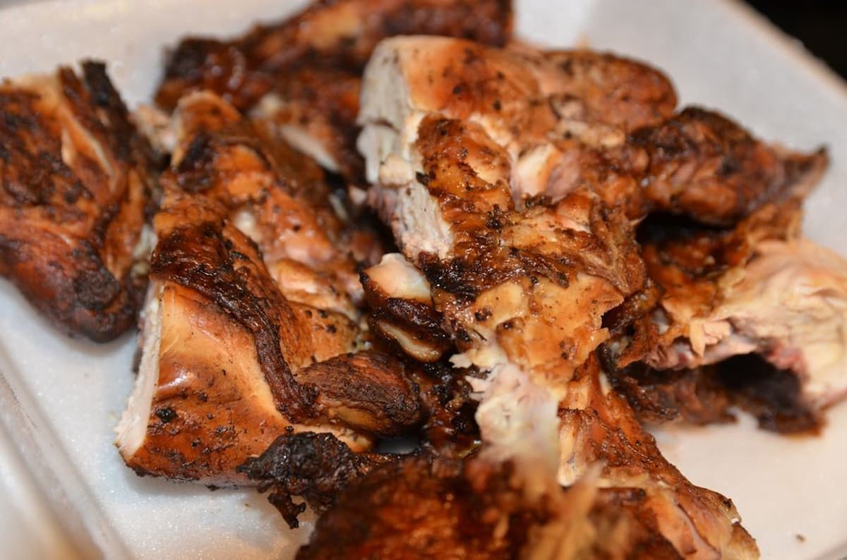 Several pieces of grilled or roasted chicken, seasoned with spices, are arranged on a white foam tray—reminiscent of meals served at fast-food chains with real chicken. The meat appears juicy and well-cooked with a slightly charred exterior.