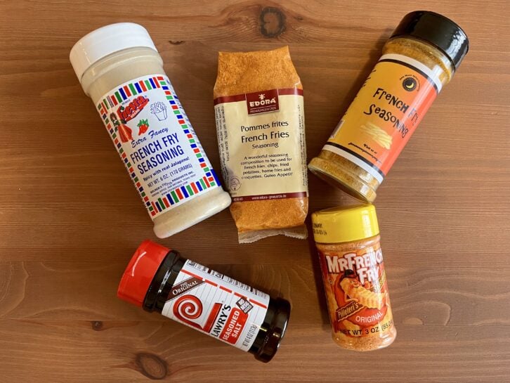 five french fry seasoning brands on a wood table