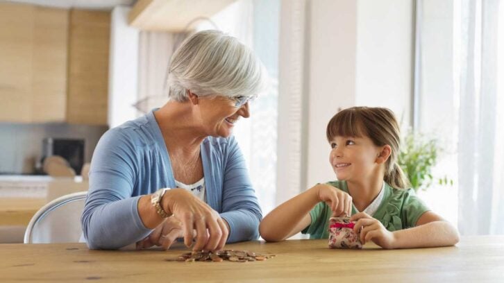 Grandma and grandaughter sitting at a kitchen table in front of coins