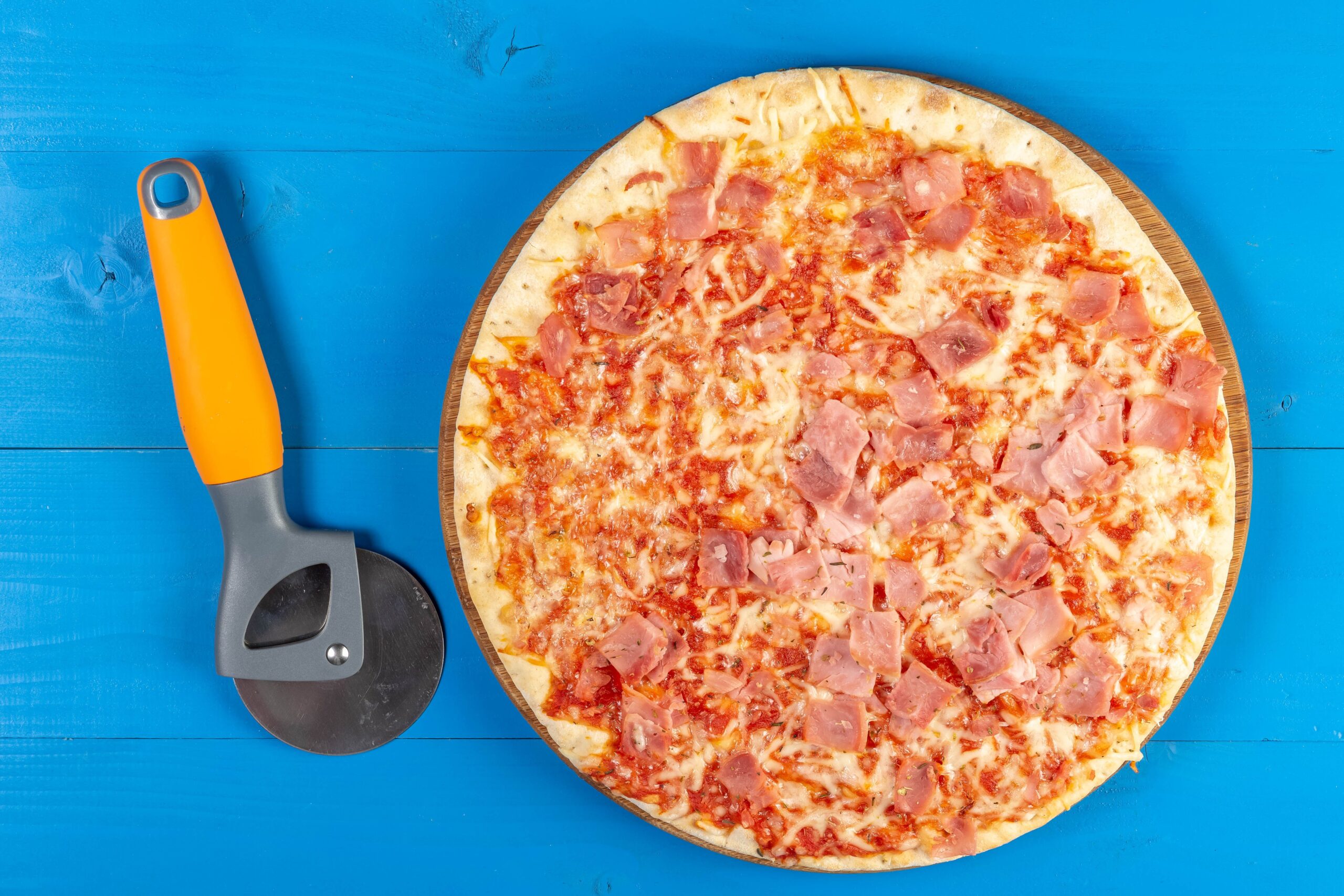 baked pizza with ham and pizza knife