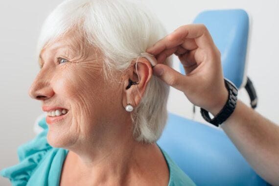 senior woman getting hearing aid adjusted at doctor office