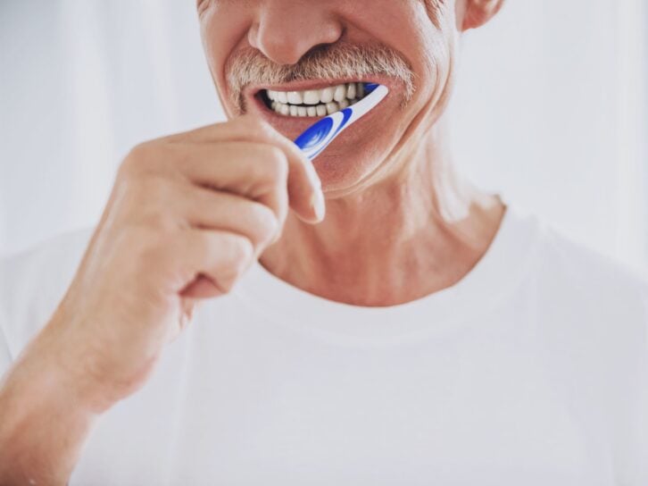 Close up. Senior Man Brushing Teeth in Bathroom. Morning Routine. Healthcare Roncepts. Elder Person at Home. Smiling Man. White Teeth. Smiling Grandfather. Dental Hygiene Concepts.