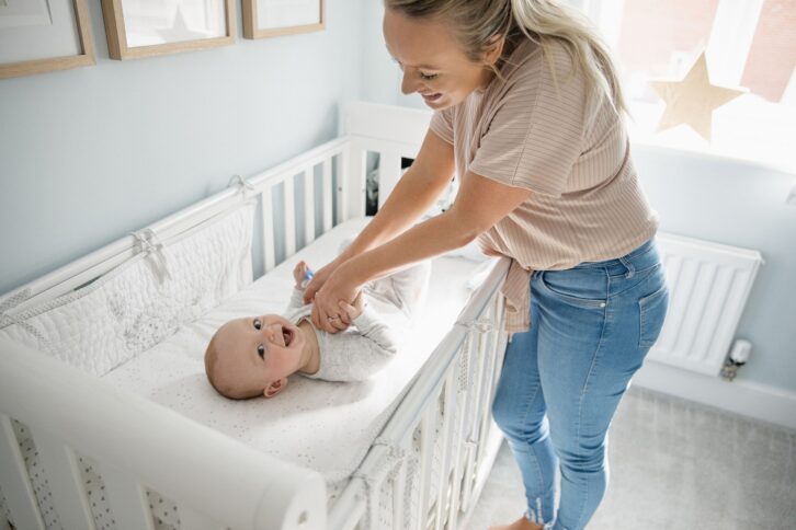 baby and mother laughing while baby is in crib