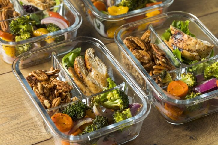meal prep with chicken, leafy greens, vegetables, and pecans