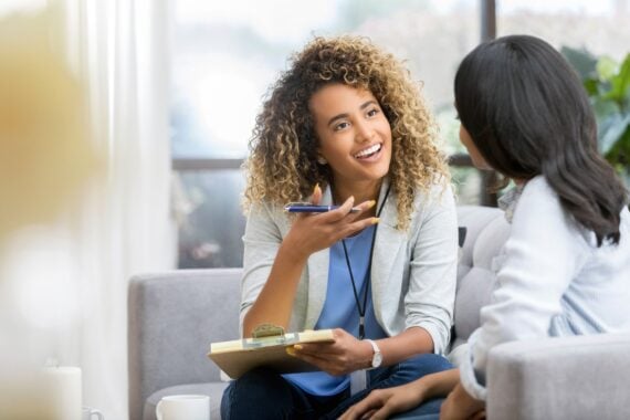 therapist encouraging young woman, seated on couch