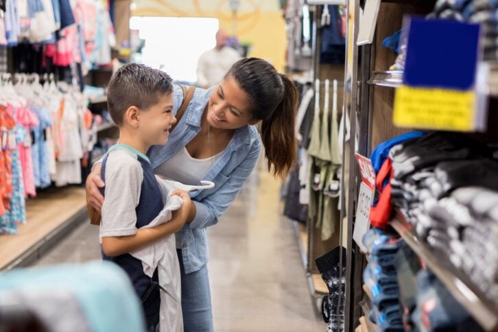 woman shopping with child in sale clothes section