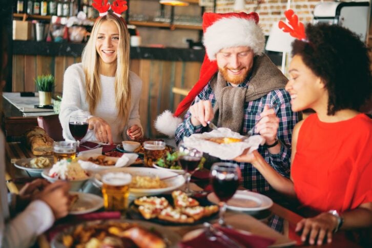 Friends having dinner at home at Christmas eve. Winter holidays concept.