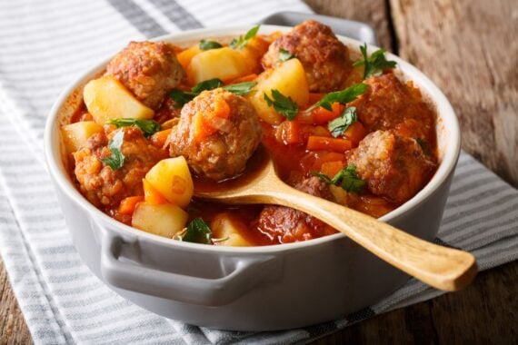 Hot stew meatball soup with vegetables in tomato sauce closeup in a pot on the table. horizontal