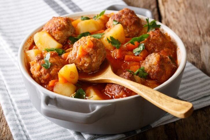 Hot stew meatball soup with vegetables in tomato sauce closeup in a pot on the table. horizontal