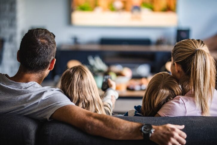 rear view of a family watching TV on sofa at home