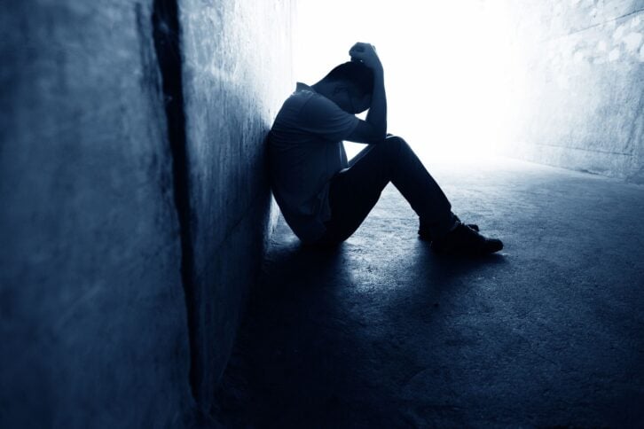 desperate man sitting in dark tunnel