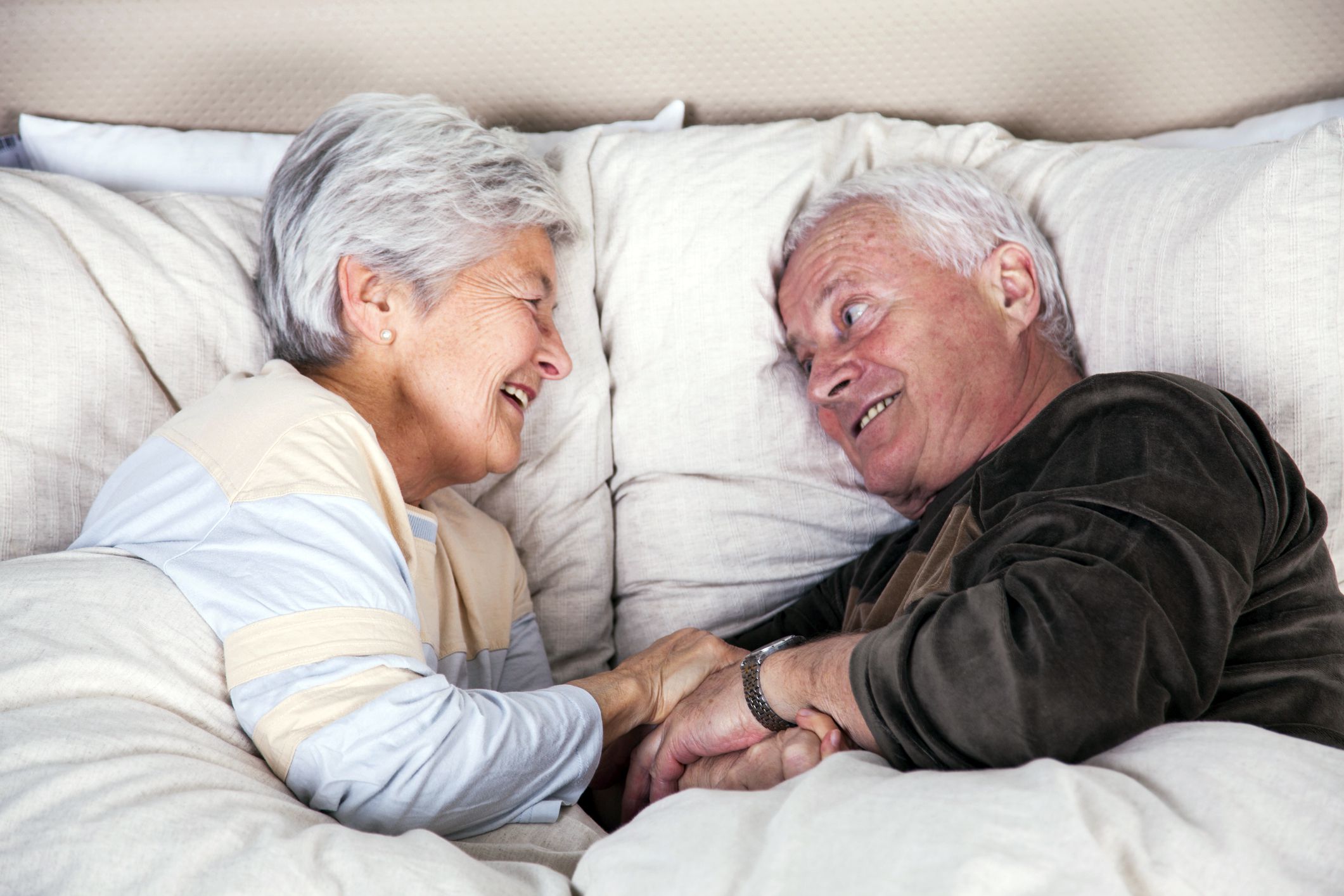 senior couple looking at each other in bed, man with very excited face and eyes lit up