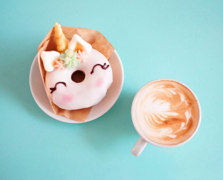 Unicorn donut with coffee on blue background. Top view. Flat lay