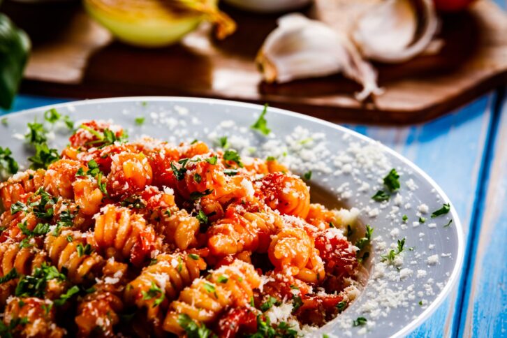 Pasta witch pork and vegetables on wooden background