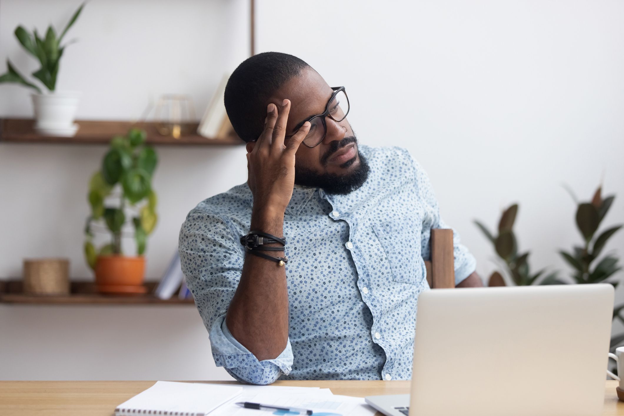 frustrated man at desk looking into distance with regret