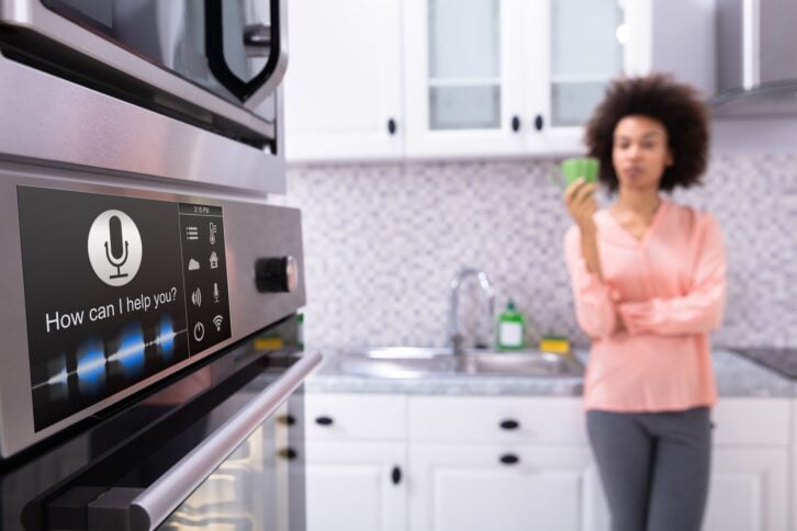 Close-up Of An Oven With Voice Recognition Function Near The Blurred Woman Standing In Kitchen