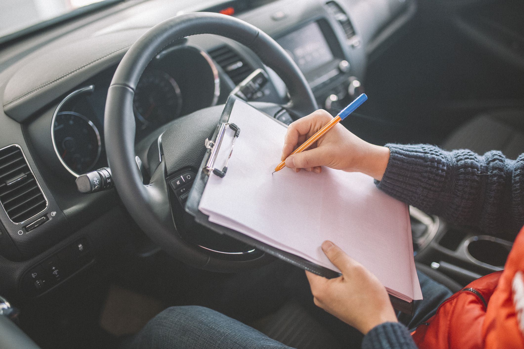 driver with notepad on steering wheel about to sign