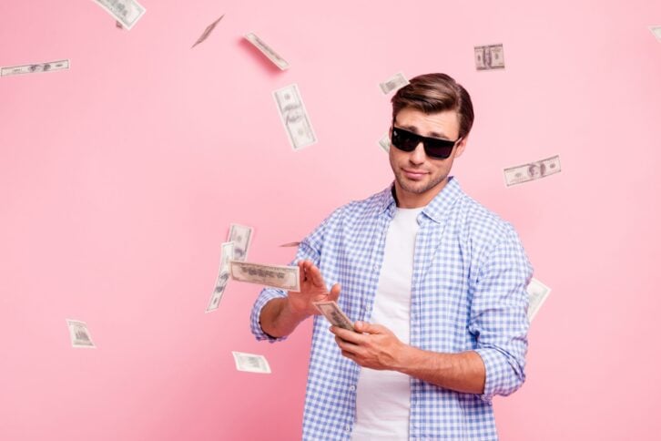 Portrait of his he nice cool trendy content attractive handsome reckless careless carefree guy wearing checked shirt throwing money away wealth isolated over pink pastel background