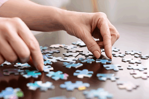 closeup of hands putting together a jigsaw puzzle