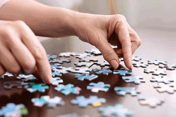 closeup of hands putting together a jigsaw puzzle