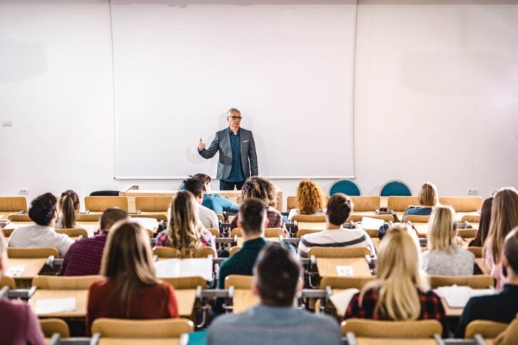 students listening to lecturer in college lecture hall