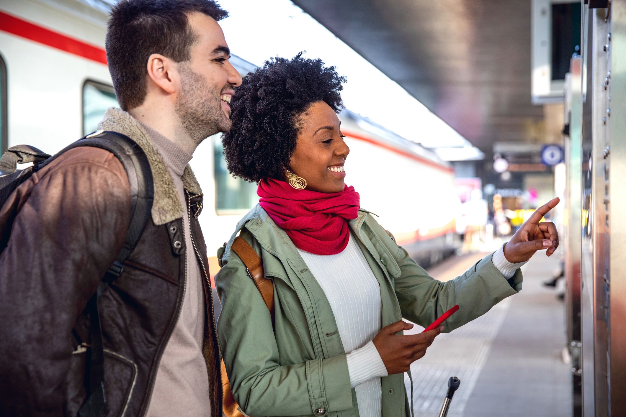 couple looking at train schedule on train platform