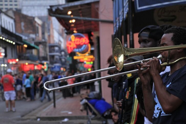 12 April 2018 - New Orleans, Louisiana / United States: Jazz musicians performing in the French Quarter of New Orleans, Louisiana, with crowds and neon lights in the background.