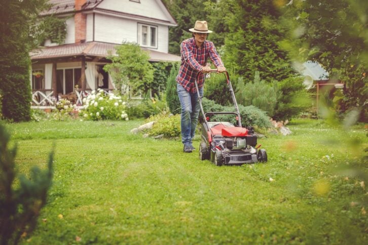 Man mowing grass near his house
