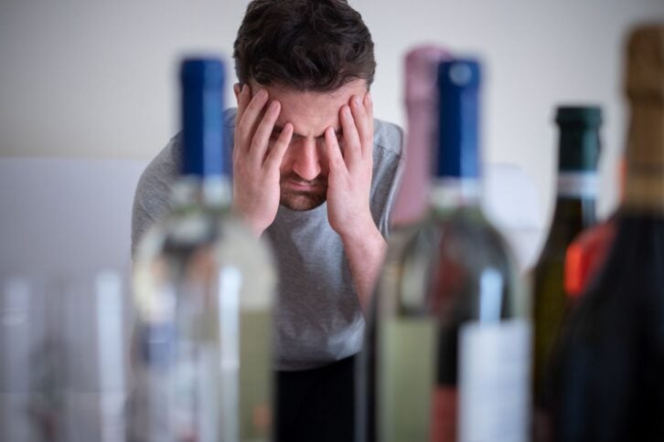 Alcohol addicted man portrait alone with spirit bottle