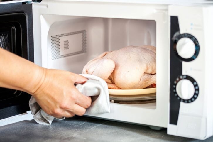 The defrozen raw chicken in the microwave. Selective focus.