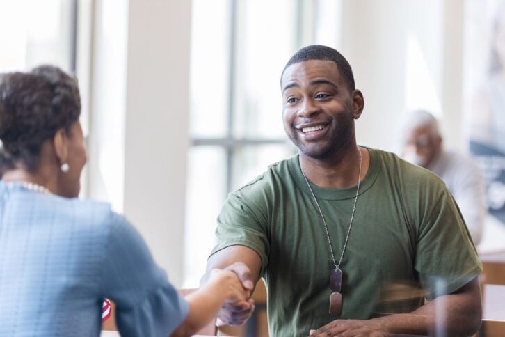 The mature adult banker and the army soldier shake hands to close the deal on his new mortgage.