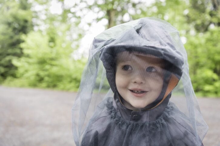 Little Redhead Boy Playing Outside on Campground and Wearing Mosquito Netting Hat