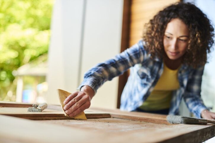 a woman sands a vintage wooden door