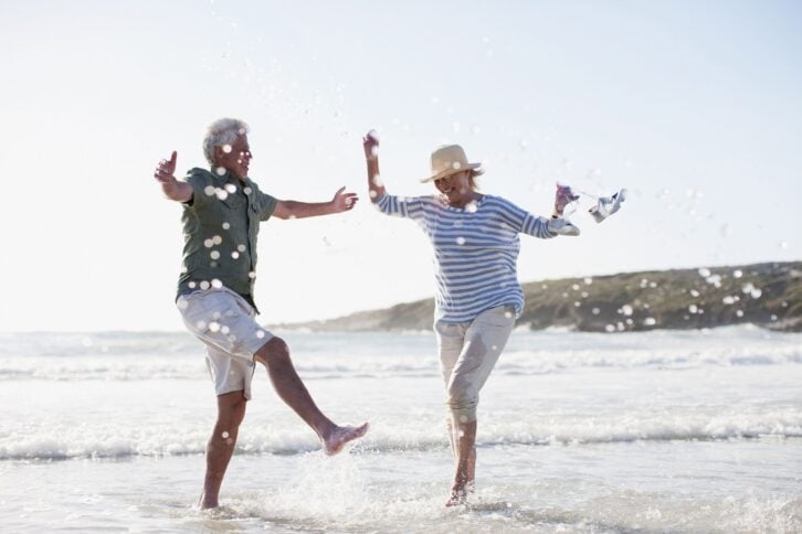 senior couple splashing in ocean