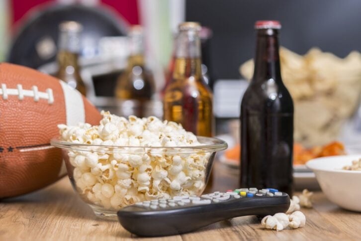 football and snacks on table with tv remote