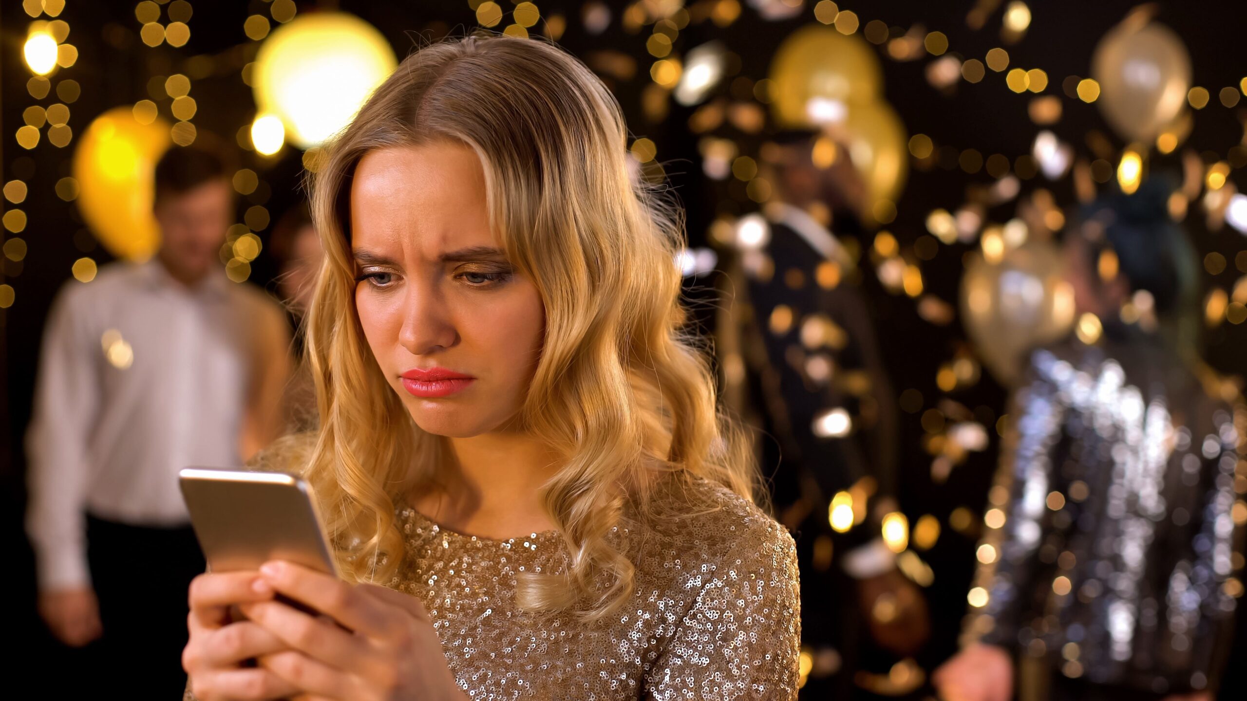 Upset chic female typing message smartphone closeup, dancing people background