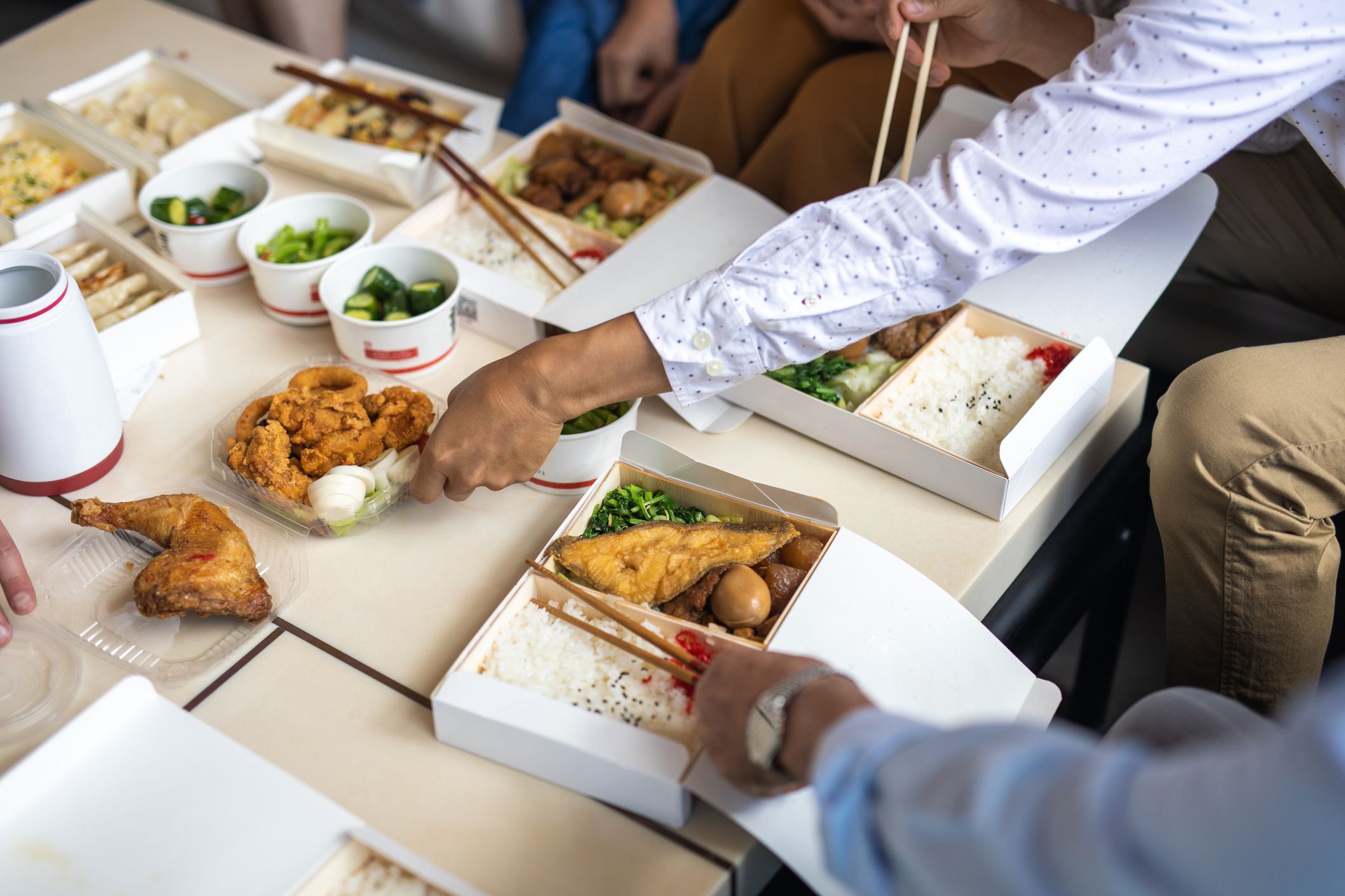 Close up of Chinese take out food, family eating with chopsticks in living room